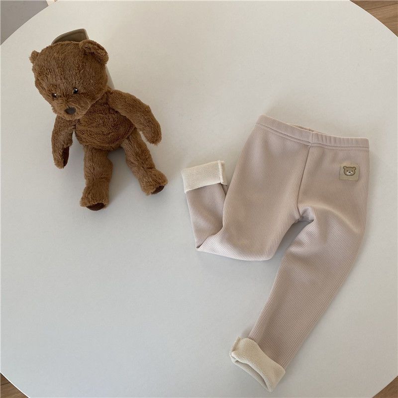 Fleece-lined girls leggings in beige color displayed with a plush teddy bear on a table.