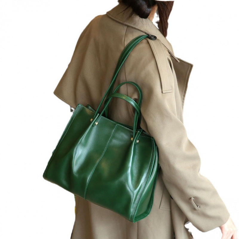 High-end leather tote bag in fruit green color, shown being carried by a woman in a stylish coat.