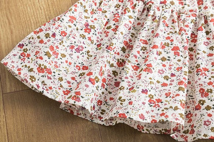 infant holiday girls dress featuring a floral pattern skirt on a wooden surface.