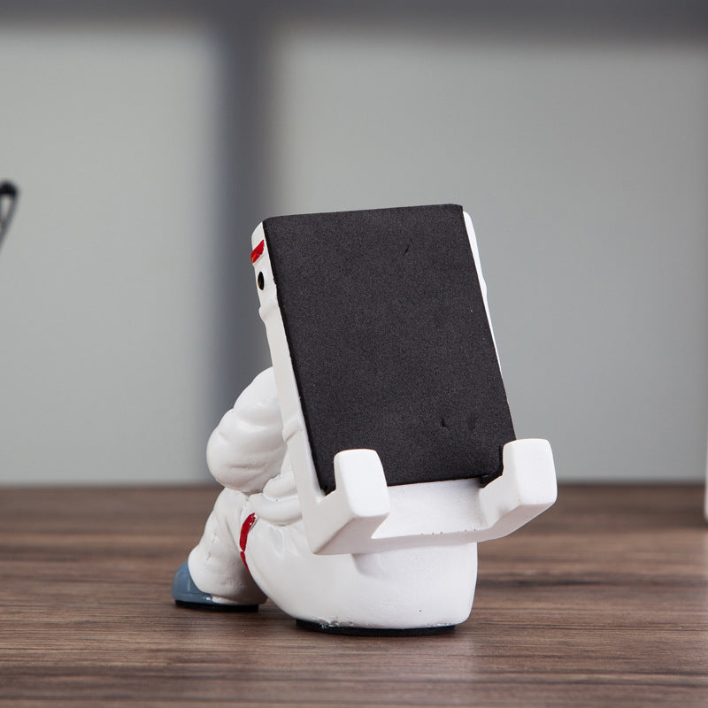 Cute astronaut phone stand showcasing a stylish astronaut shape, perfect for holding mobile devices on a desk.