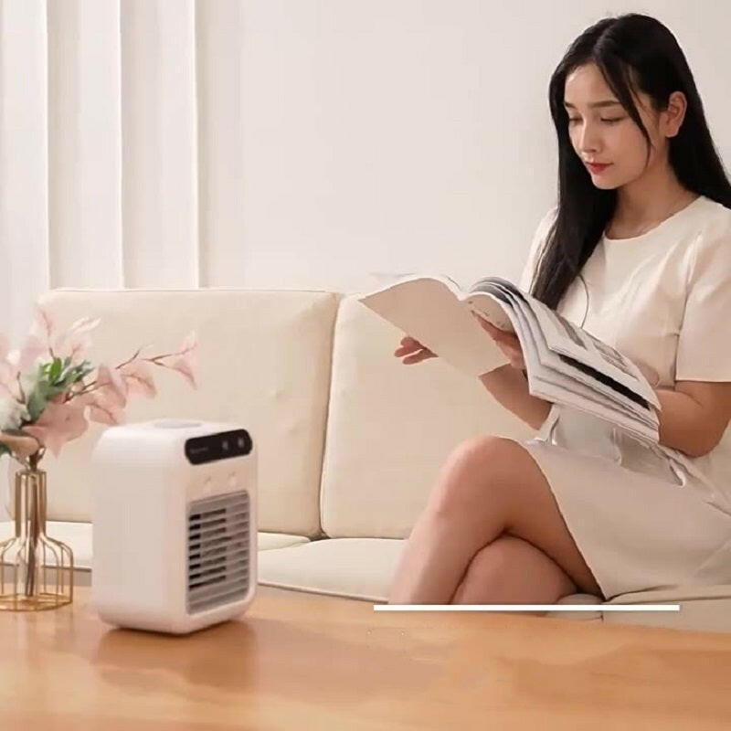 Portable Air Cooler Fan with Water Cooling next to a woman reading a magazine in a cozy living space.