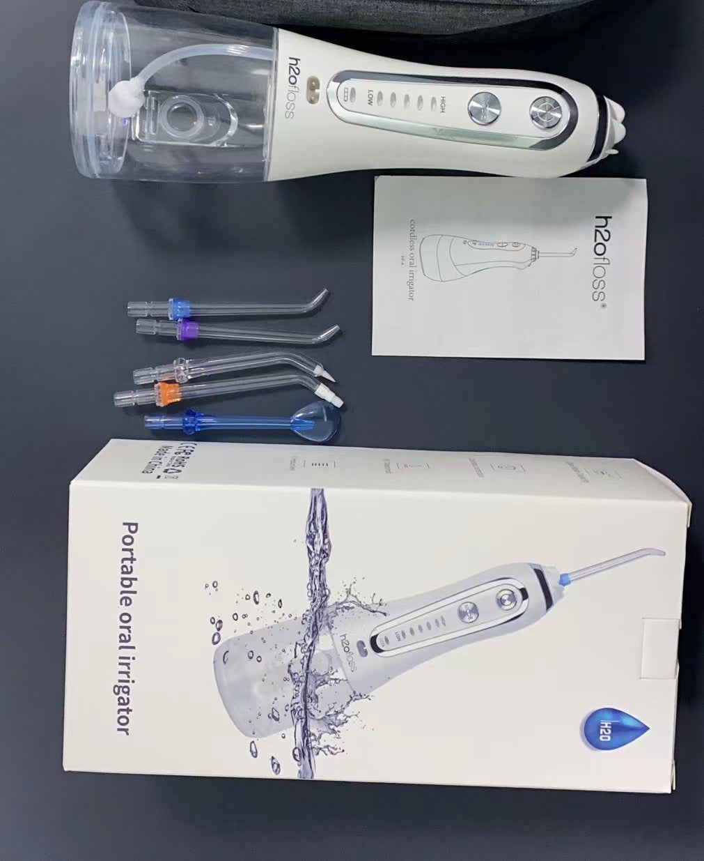 H2ofloss portable water flosser with accessories and packaging displayed on a flat surface.