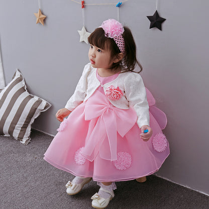 Girl wearing a pink princess dress for girls with flower details and a matching headband, sitting near decorative stars.