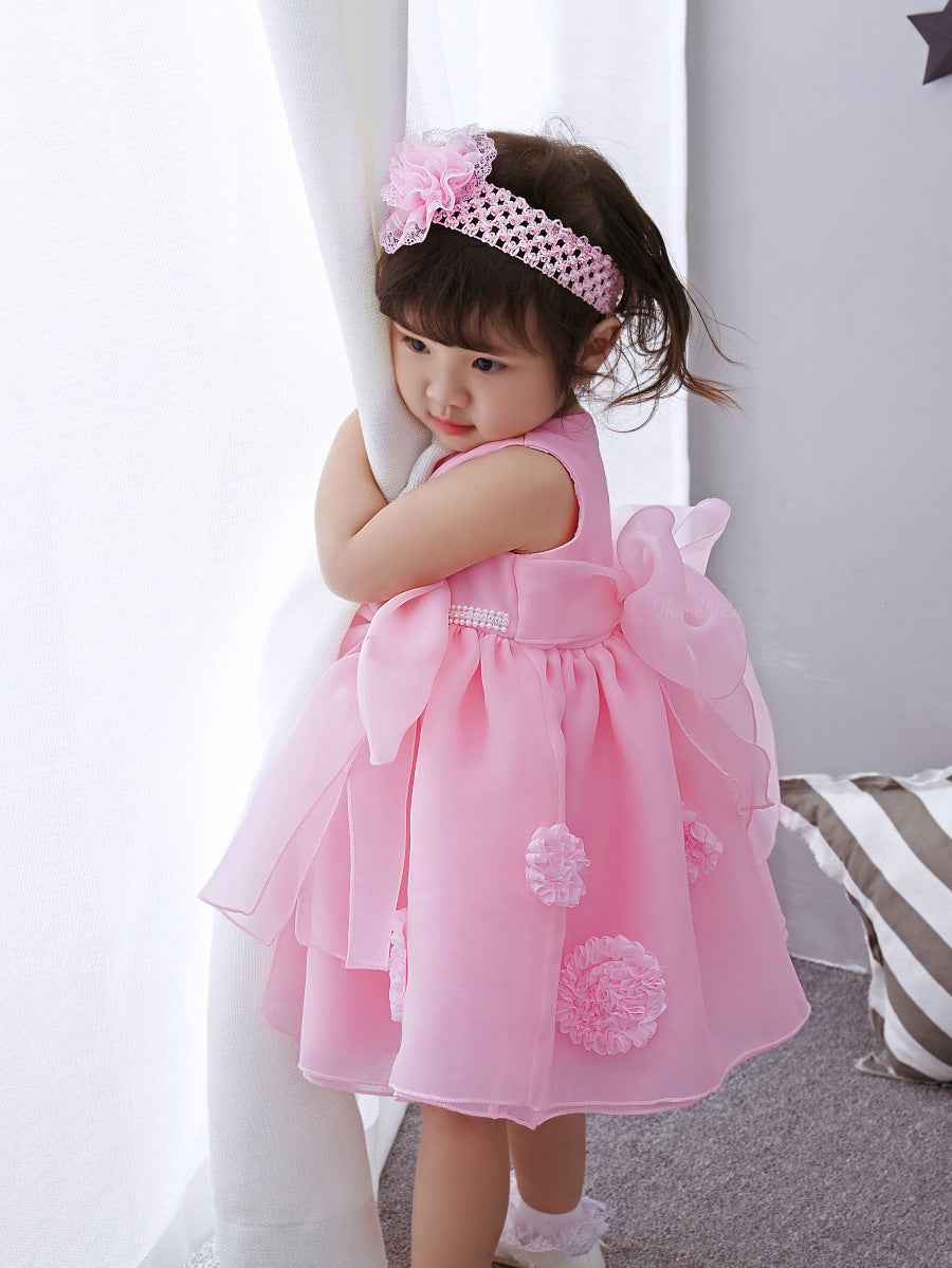Little girl in a pink dress with bows, wearing a matching headband, showcasing a pink princess dress for girls.
