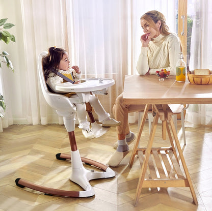 Luxury baby high chair with adjustable seat height and removable tray, featuring a child enjoying a meal.