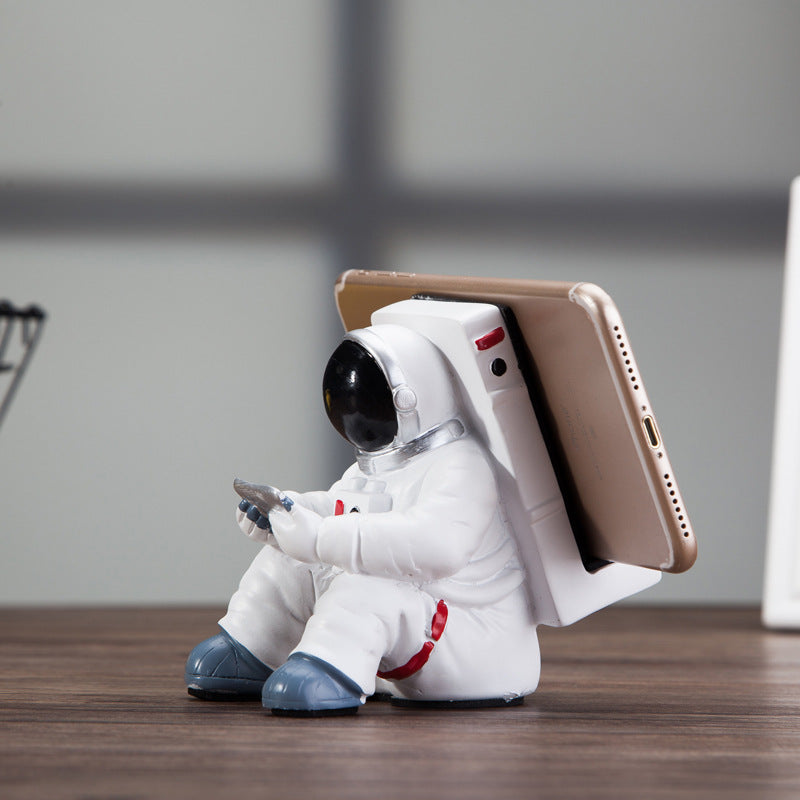 Cute astronaut phone stand holding a smartphone, stylish desktop holder for students, creative gift and decoration.