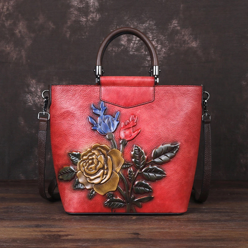 Vintage leather tote bag featuring a floral embossed design on a vibrant red background.