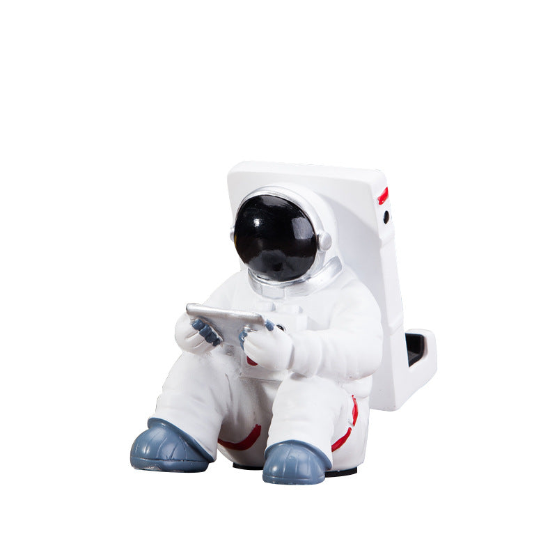 Cute astronaut phone stand designed for desktops, featuring a spaceman holding a mobile. Ideal small desk decoration.