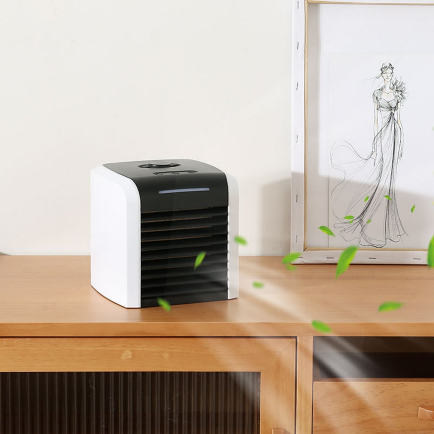 Portable air conditioner for office use on a wooden desk with green leaves blowing near it.