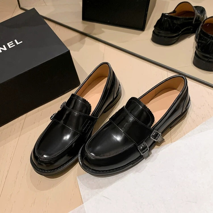 Retro distressed brown leather shoes displayed with a black designer box in the background, featuring a sleek loafer style.
