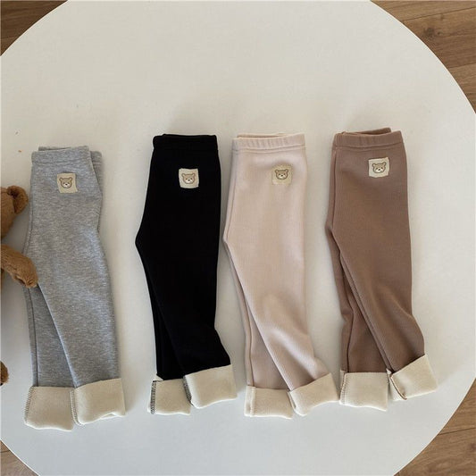 fleece-lined girls leggings in solid colors: gray, black, beige, and brown on a circular table.