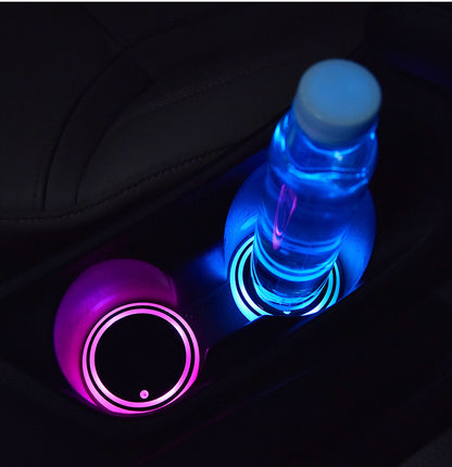 LED light-up car coaster with colorful lights illuminating a water bottle and cup in a vehicle's cup holder.