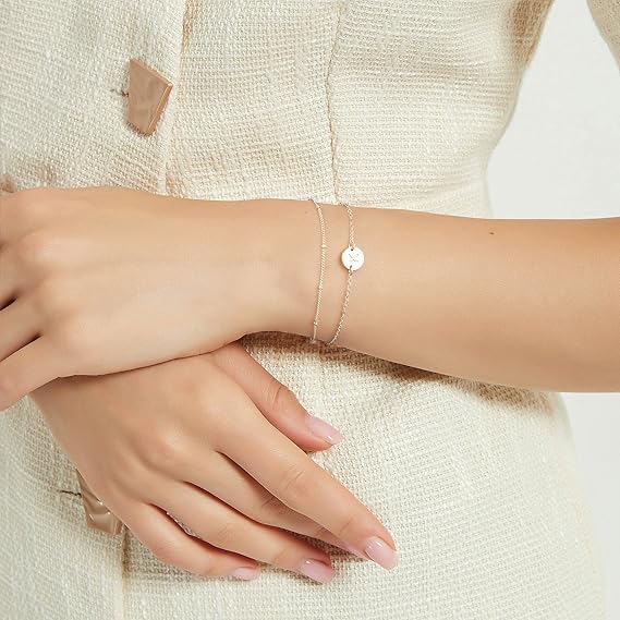 14K Gold Dainty Gold Bracelets worn on a woman's wrist, featuring a delicate chain and charm.