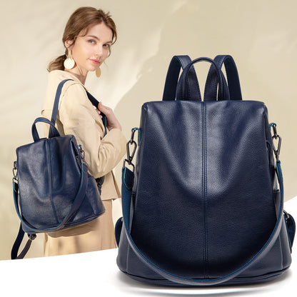 Versatile large-capacity anti-theft leather backpack in navy blue, modeled by a woman wearing stylish accessories.