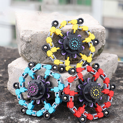 Deformed fidget spinner toys for children in blue, red, and yellow colors on a stone surface.