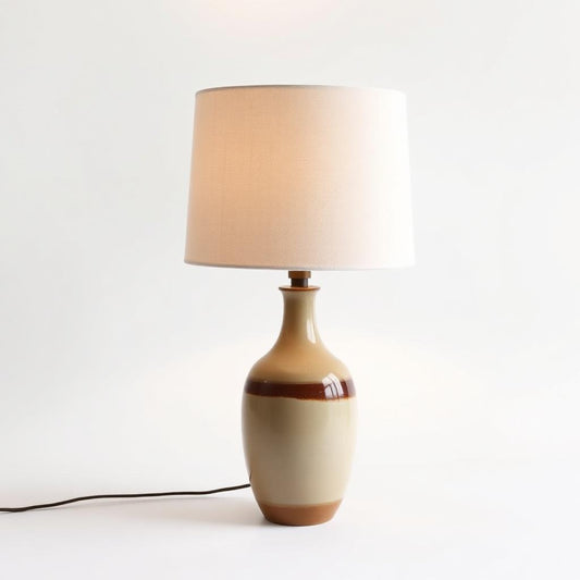 Linen Glow Table Lamp with handcrafted ceramic base and warm linen shade, providing a soft golden ambience.