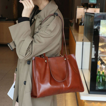 A woman carrying a high-end leather tote bag in a rich brown color, complementing her stylish outfit.