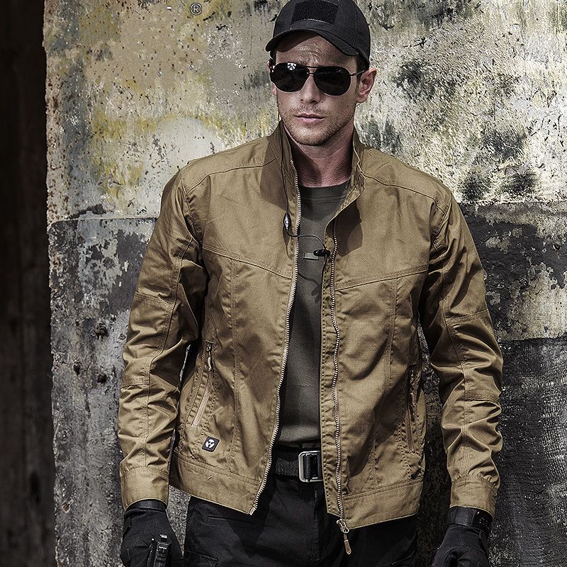 Man wearing a windproof military style jacket in a rugged outdoor setting, showcasing its durable design.