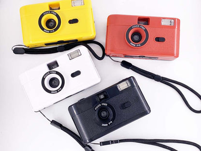 Four colorful non-disposable retro film cameras in yellow, red, white, and black arranged together.