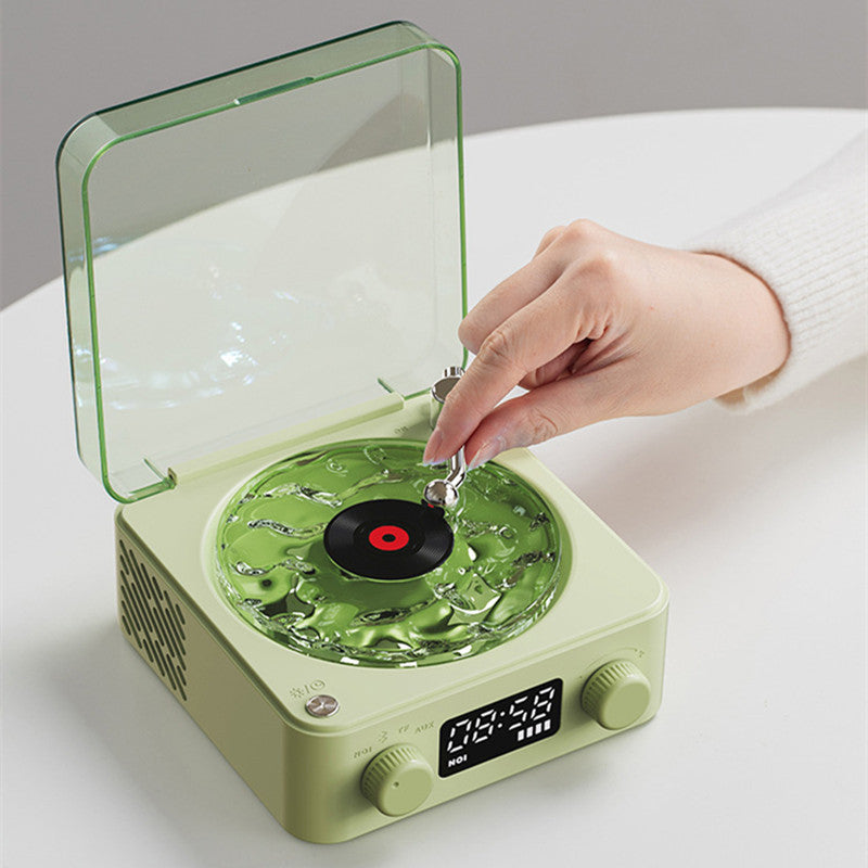 Retro Turntable Wireless Bluetooth Speaker with green design and hand placing stylus on record.